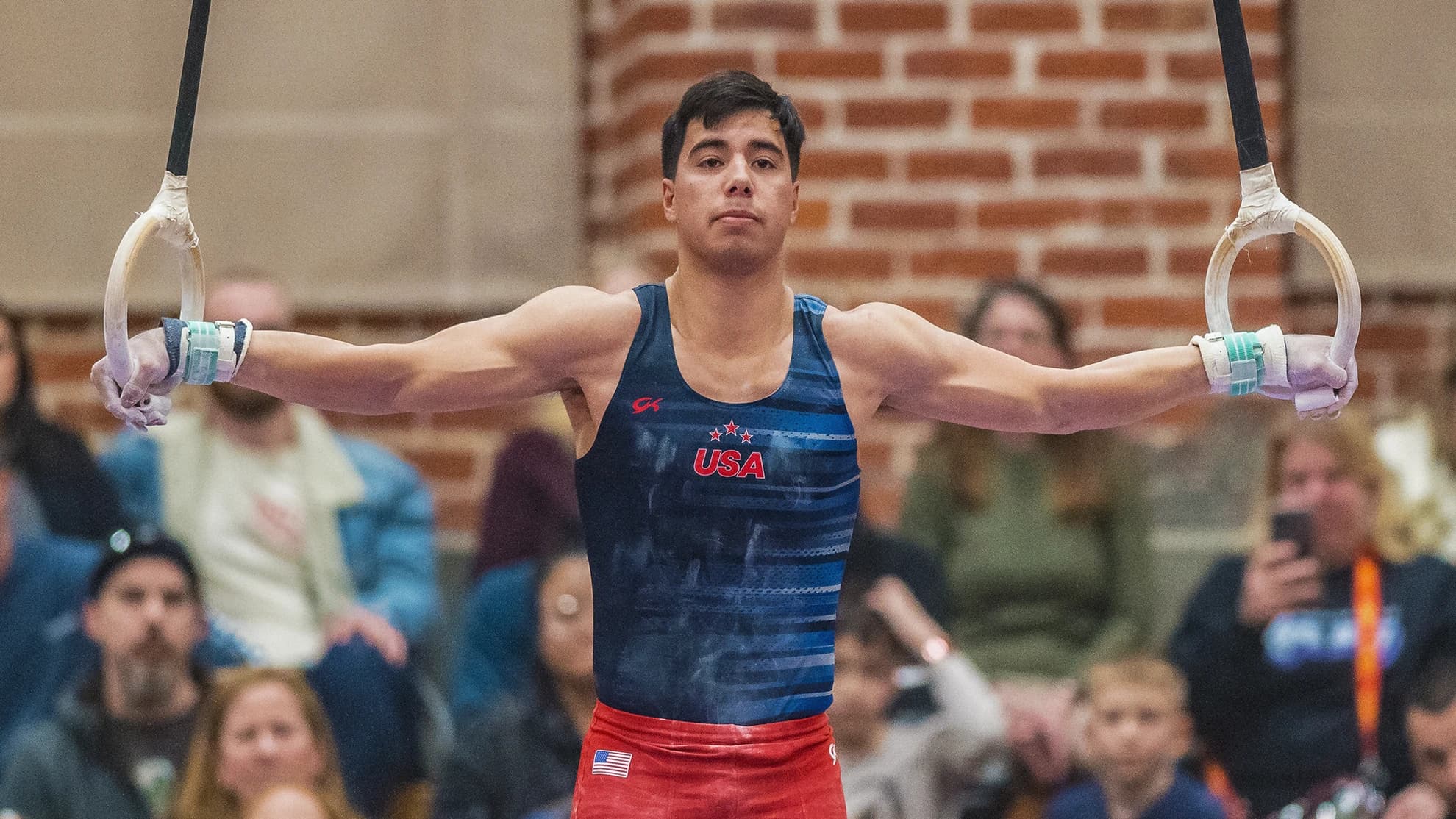 Jeremy Bischoff performing an iron cross on rings in a USA National Team leotard